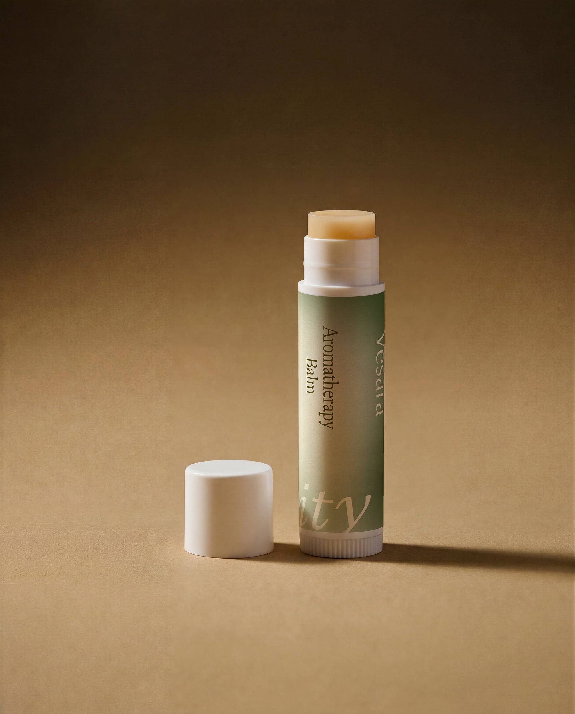 Vesara Clarity Aromatherapy Balm tube standing upright with white cap removed and sitting off to the left, both standing on warm beige surface