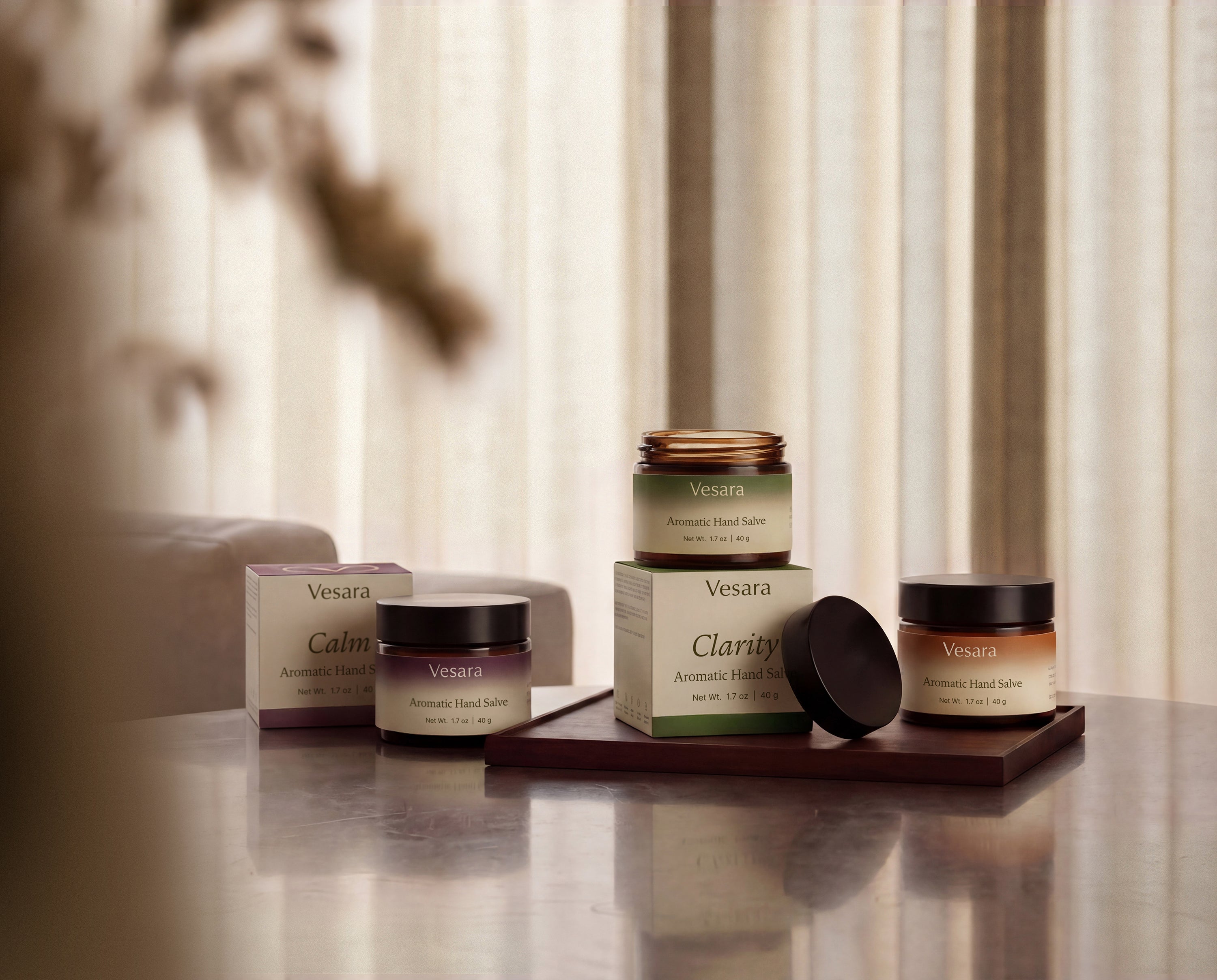 Full Vesara Aromatic Hand Salve collection with jars and boxes scattered on warm surface including Calm and Clarity